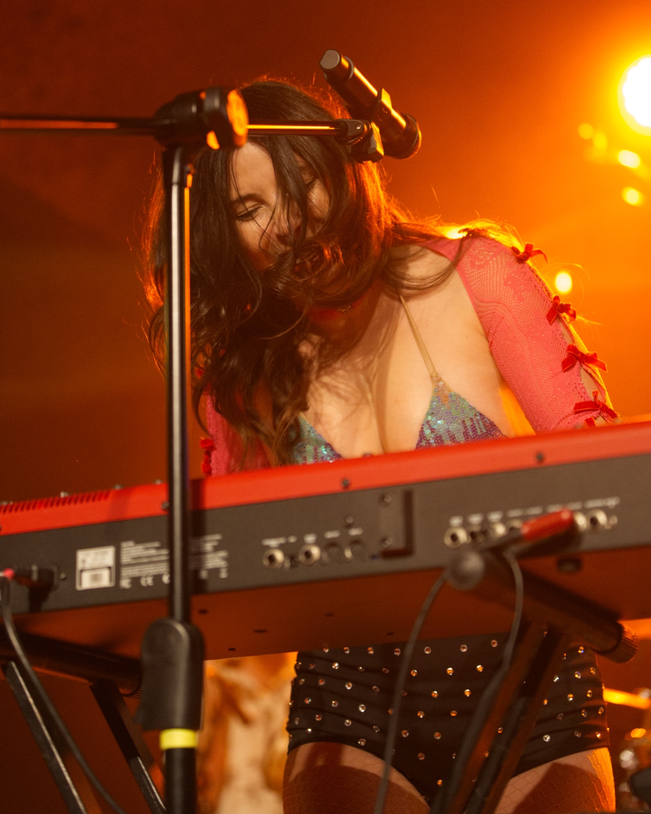 Keyboardist singing under warm stage lighting