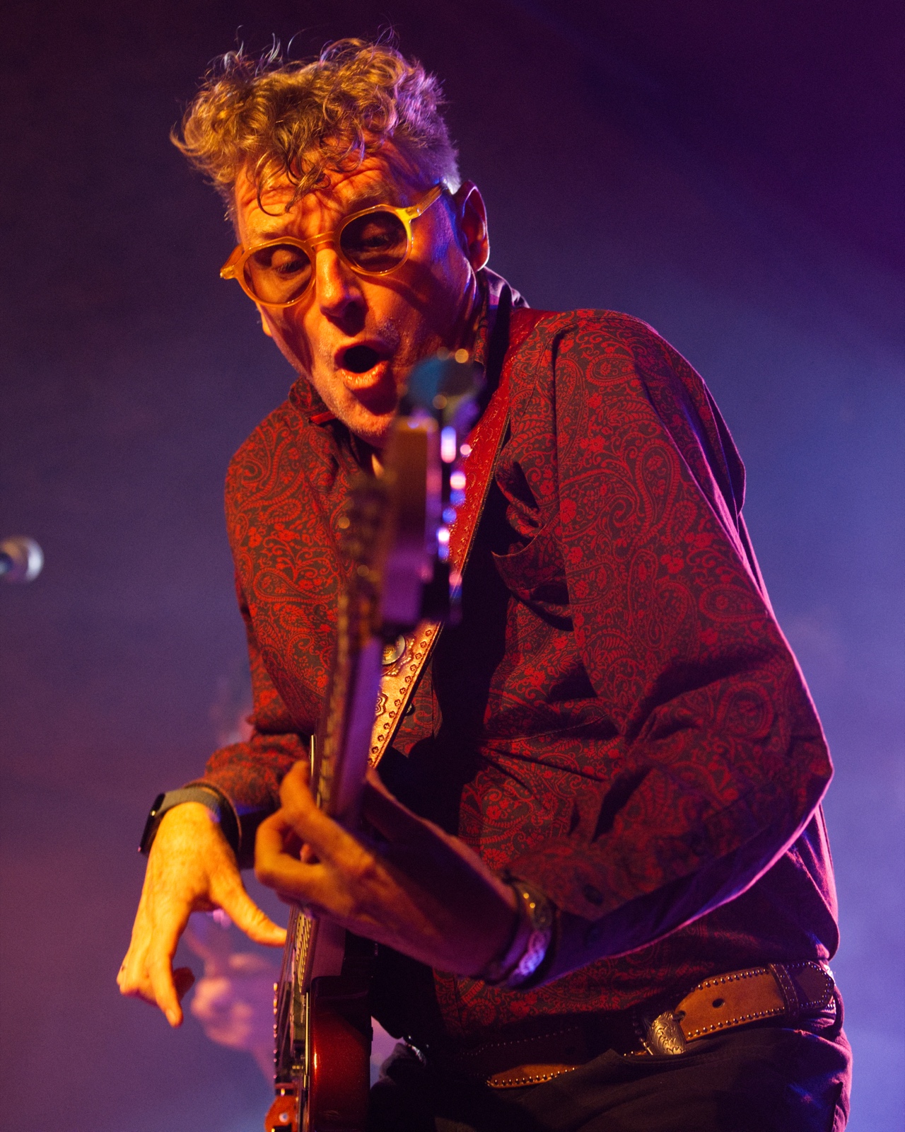 Guitarist performing with intense expression under moody lighting