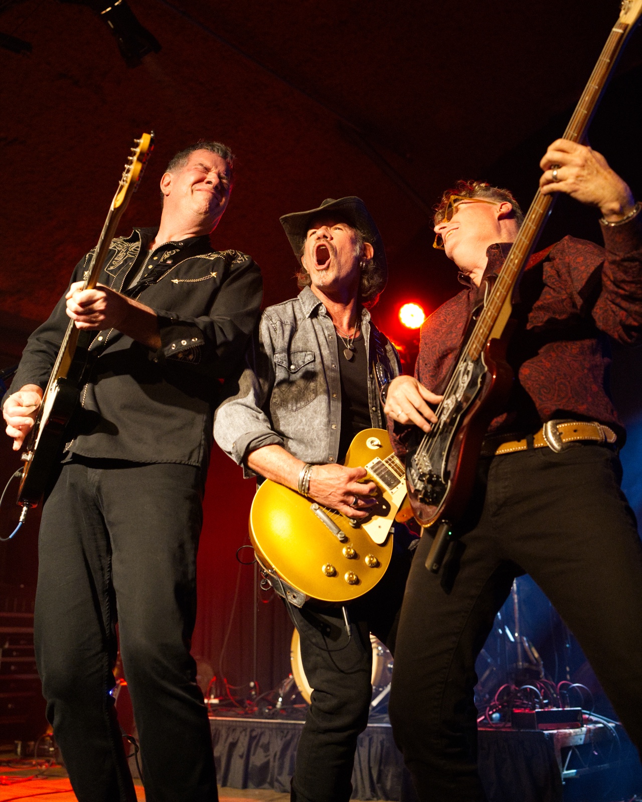 Three band members performing together on stage