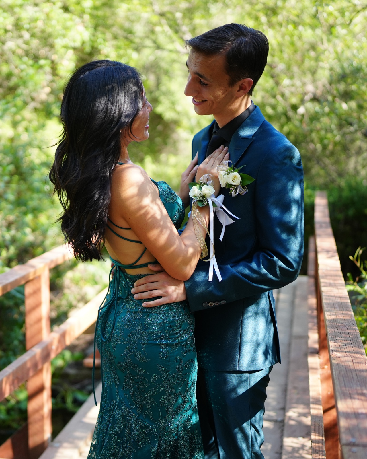 Prom couple embracing tenderly on a wooden bridge