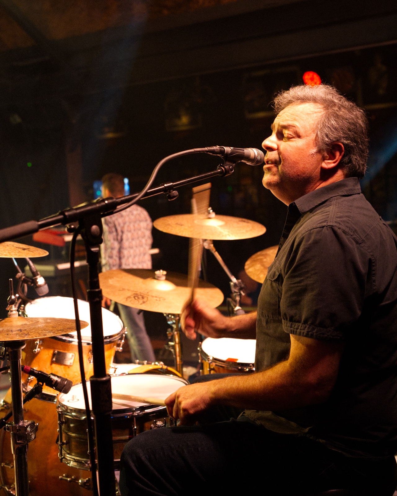 Drummer singing into the mic while playing cymbals