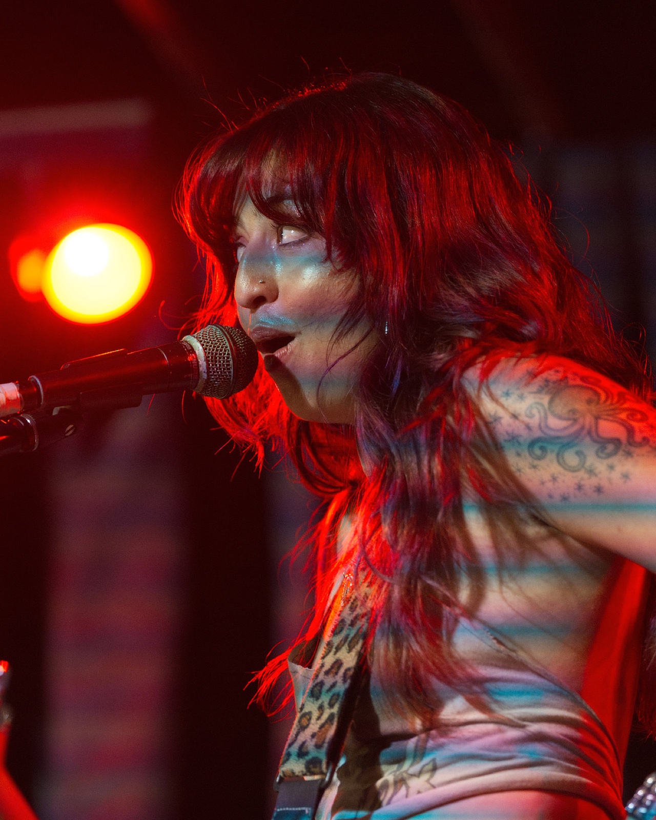 Close-up portrait of a singer with red hair under red stage light