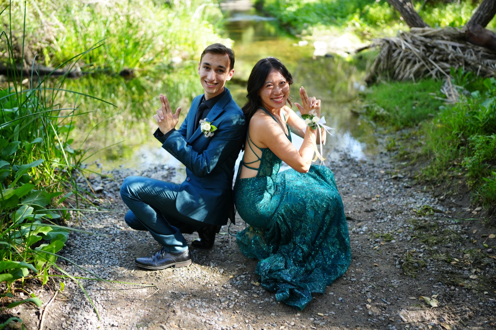 Prom couple posing playfully by a creek
